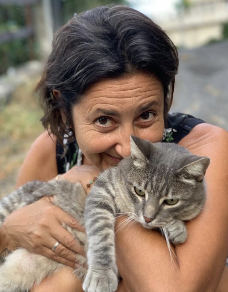 Nicoletta guarda sorridente verso l'obiettivo mentre abbraccia il gatto di nome Silver